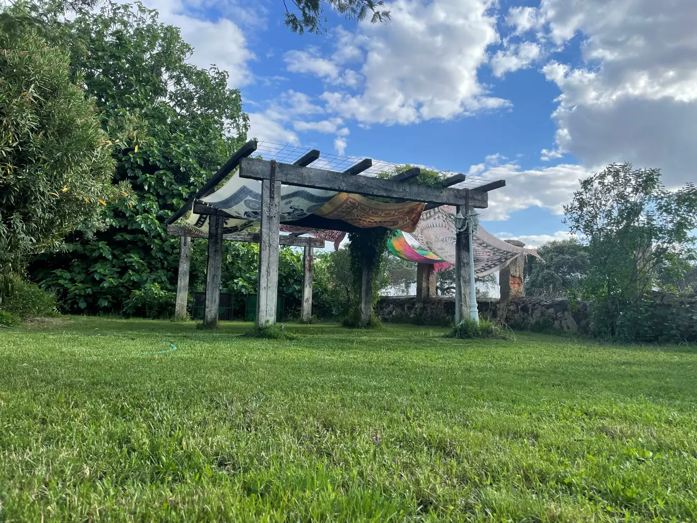 Pérgola con telas sobre el jardín de Vibrabuena durante el día.